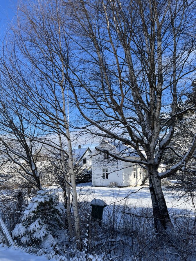Et gammelt hus i snø og solskinnsvær.