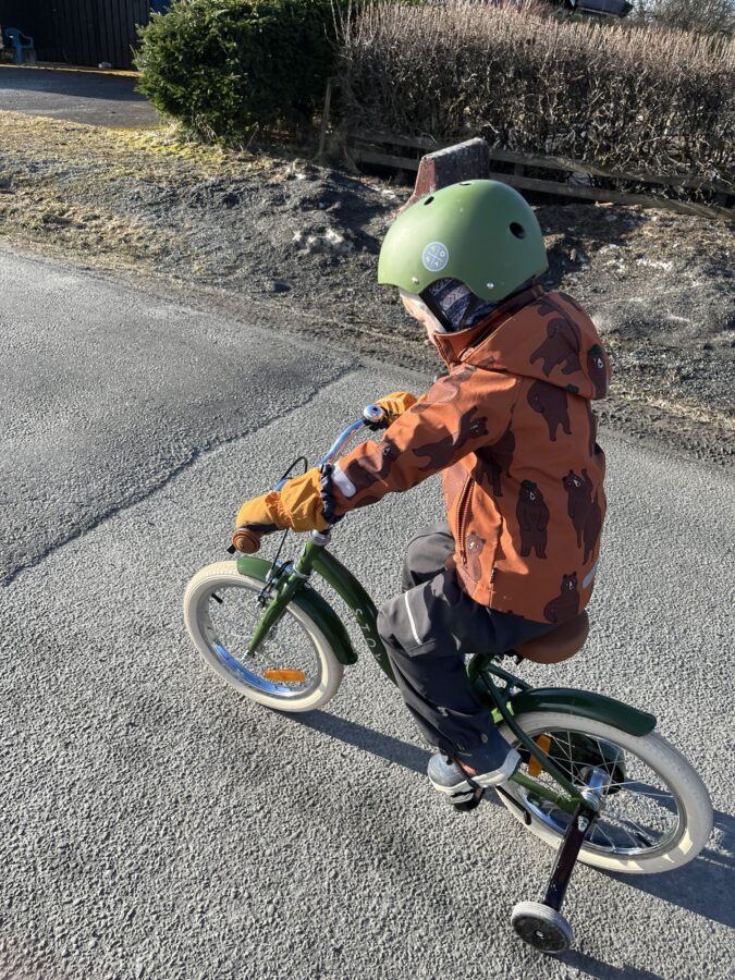 Gutt på sykkel med støttehjul.